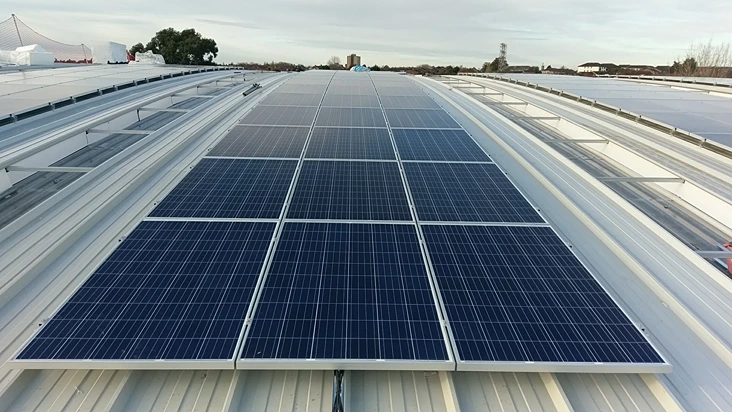 black solar panels installed on a white industrial warehouse roof